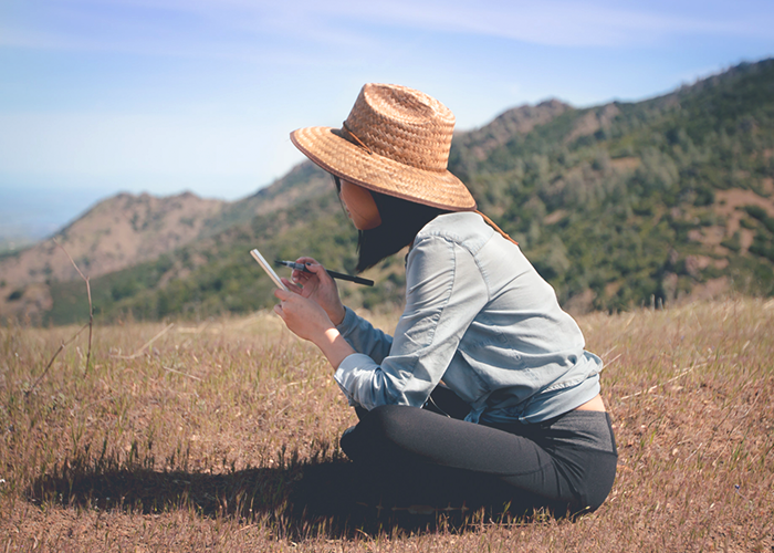 young-woman-sitting-on-grass-writing