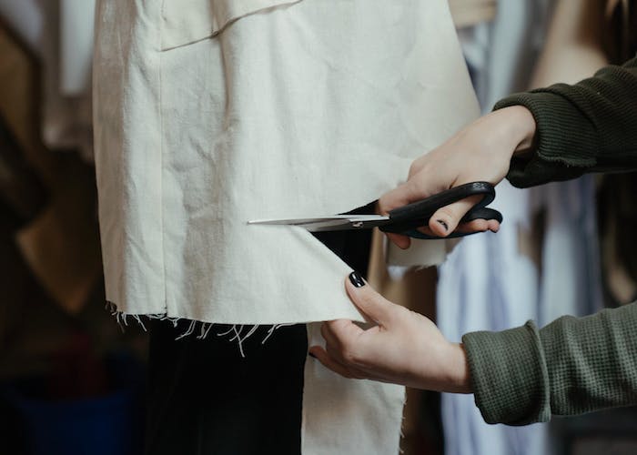 Woman cutting clothing with a pair of scissors for a DIY fashion style