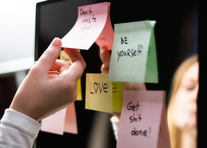 woman-removing-adding-post-it-positive-affirmations-to-mirror