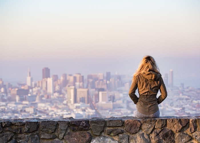 woman-sitting-on-rock-ledge-over-looking-the-city